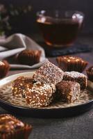 Healthy candies made from figs, dates, nuts, coconut and sesame seeds on a plate vertical view photo