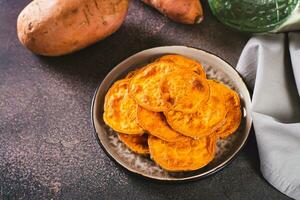 hecho en casa rebanado horneado dulce patata en un plato en el mesa foto