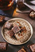 Sugar free candies made from fruit paste, nuts and sesame seeds on a plate vertical view photo