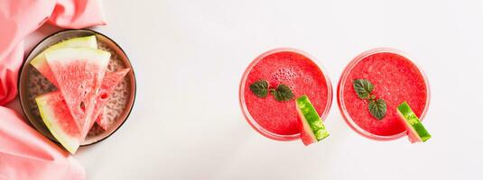 Watermelon lemonade with watermelon pieces in glasses on pink background top view web banner photo