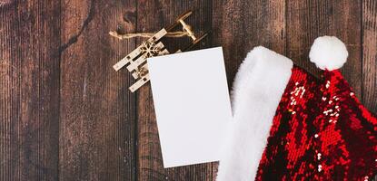 List of gifts with santa claus hat, cardboard fir trees and sleigh on the table top view web banner photo