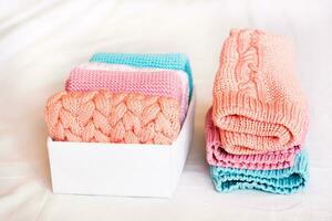 Organization and order. A stack of knitted clothes next to a box of neatly folded items photo