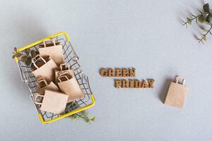 Green Friday inscription and paper bags in a shopping cart on a green background top view photo