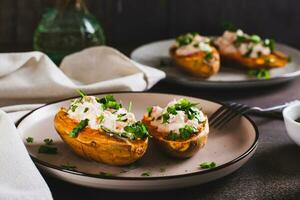 Baked sweet potato stuffed with ricotta, tomatoes and herbs on a plate photo