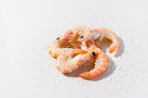 Raw thawed prawns with water drops on a pink background. Mediterranean food. Hard light photo