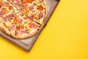 Takeaway and delivery. Ready-to-eat pizza in cardboard box on yellow background photo