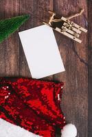 Gift list, christmas tree, sled and santa claus hat on table top and vertical view photo