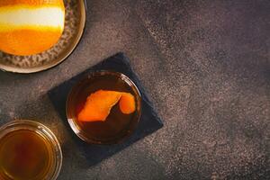 Hard alcoholic brown butter cocktail with orange zest in a glass top view photo