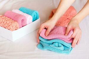 Organization and order. Female hands fold knitted clothes next to a box with neatly folded things photo