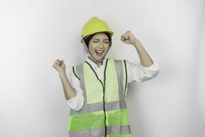 A successful young woman labor is wearing safety helmet and vest, isolated by white background. Labor's day concept. photo