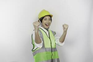 A successful young woman labor is wearing safety helmet and vest, isolated by white background. Labor's day concept. photo