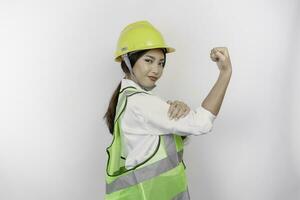 un retrato de asiático mujer labor usa la seguridad casco y chaleco, demostración fuerte gesto por levantamiento su brazos y músculos sonriente con orgullo mano de obra día concepto. foto