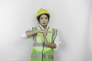 Hispano mujer labor vistiendo la seguridad casco y chaleco haciendo hora fuera gesto con manos y grave rostro, aislado blanco antecedentes foto