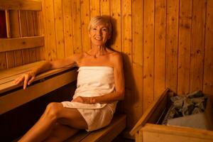 Mature woman is relaxing in sauna. Healthy lifestyle for elderly people. Spa concept. photo