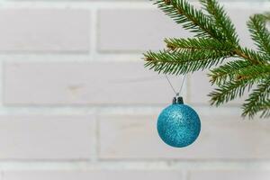 blue Christmas ball on the branches of a Christmas tree against white brick wall photo