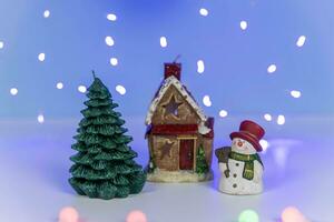 A snowman near a fabulous winter house and a Christmas tree photo