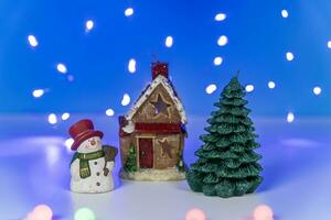 A snowman near a fabulous winter house and a Christmas tree photo