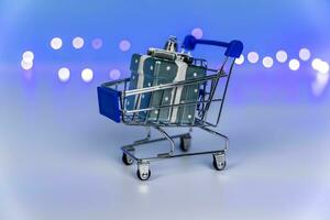 a supermarket cart with a gift in a box on a blue background with blurred lights photo