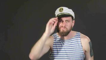 Handsome bearded captain tiding himself isolated on dark gray background video