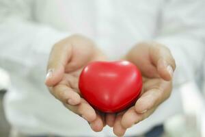 Man holding red heart shaped rubber. photo