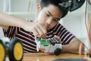 Asian teenager doing robot project in science classroom. technology of robotics programing and STEM education concept. photo