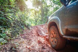 Offroad travel and driving concept, Wheel closeup in a countryside landscape with a muddy road, Off-road travel on muddy road. photo