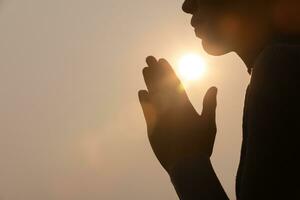 silueta de mujer en posición de oración, manos rezando con fe en la religión y creencia en Dios en un fondo oscuro. poder de la esperanza o el amor y la devoción. gesto de manos namaste o namaskar. foto