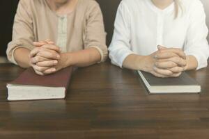 Two women praying worship believe.  praying and praise together at home.  Praying hands with faith in religion and belief in God, Christian Religion concept. photo