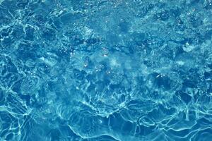 Defocus blurred transparent blue colored clear calm water surface texture with splashes reflection. Trendy abstract nature background. Water waves in sunlight with copy space. Blue watercolor shine. photo