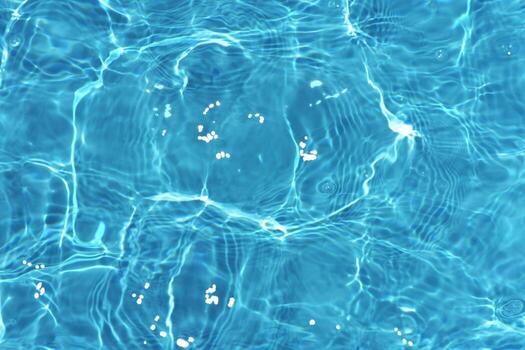 Blue water with ripples on the surface. Defocus blurred transparent blue colored clear calm water surface texture with splashes and bubbles. Water waves with shining pattern texture background. photo