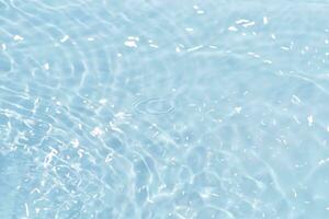 Blue water with ripples on the surface. Defocus blurred transparent blue colored clear calm water surface texture with splashes and bubbles. Water waves with shining pattern texture background. photo