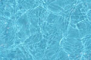 Blue water with ripples on the surface. Defocus blurred transparent blue colored clear calm water surface texture with splashes and bubbles. Water waves with shining pattern texture background. photo