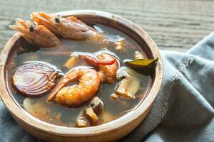 Bowl of thai tom yum soup on the wooden table photo
