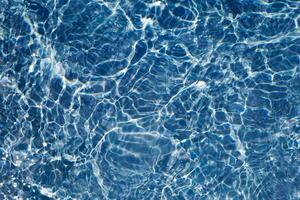 Blue water with ripples on the surface. Defocus blurred transparent blue colored clear calm water surface texture with splashes and bubbles. Water waves with shining pattern texture background. photo