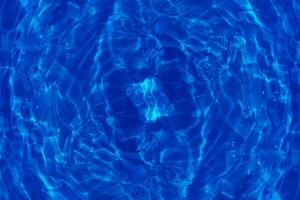 Defocus blurred transparent blue colored clear calm water surface texture with splashes reflection. Trendy abstract nature background. Water waves in sunlight with copy space. Blue watercolor shine. photo