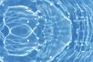 Blue water with ripples on the surface. Defocus blurred transparent blue colored clear calm water surface texture with splashes and bubbles. Water waves with shining pattern texture background. photo