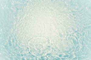 Defocus blurred transparent blue colored clear calm water surface texture with splashes and bubbles. Trendy abstract nature background. Water waves in sunlight with copy space. Blue watercolor shining photo