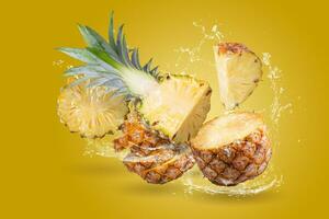 Water Splashing on Split Pineapple Fruit isolated over yellow background. photo