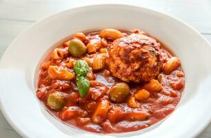 Portion of minestrone soup with meatball photo