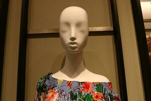 A mannequin stands on a display window in a supermarket. photo