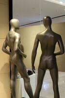 A mannequin stands on a display window in a supermarket. photo