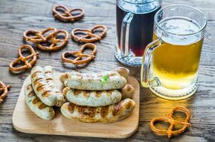 A la parrilla salchichas con pretzels y tazas de cerveza foto