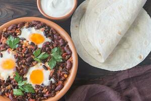 Bowl of chipotle bean chili with baked eggs photo