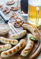 Grilled sausages with pretzels and mugs of beer photo