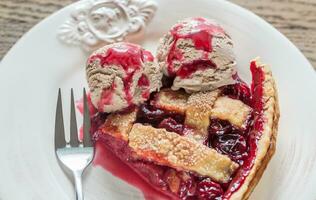 Slice of cherry pie with balls of chocolate ice cream photo