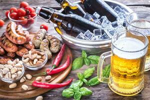 Grilled sausages with appetizers and mugs of beer photo