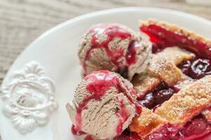 Slice of cherry pie with balls of chocolate ice cream photo