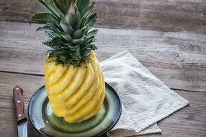 Pineapple on the plate on the wooden background photo