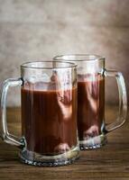Two mugs of hot chocolate on the wooden background photo
