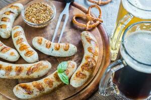 A la parrilla salchichas con pretzels y tazas de cerveza foto